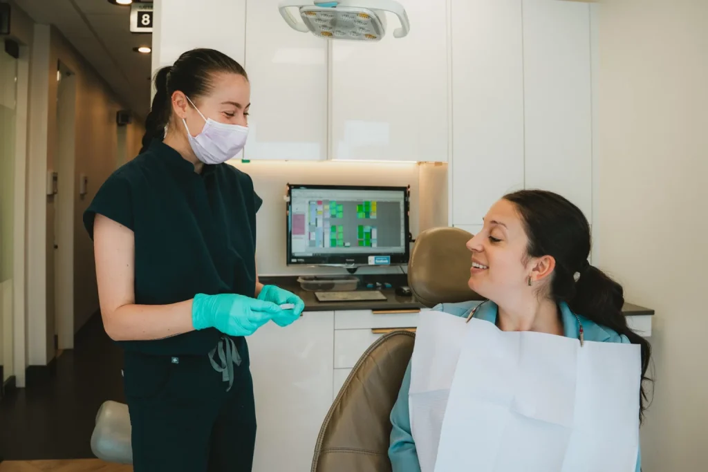 Patiente discutant de son traitement avec une professionnelle en clinique dentaire.