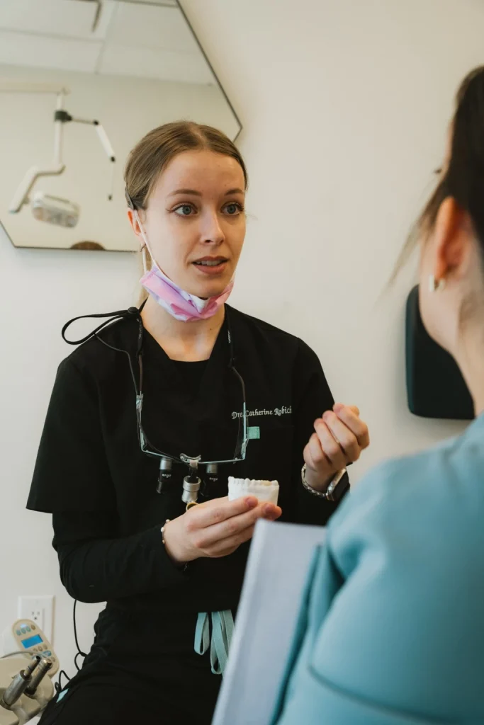 Dentiste expliquant un plan de traitement à une patiente à l’aide d’un modèle dentaire.