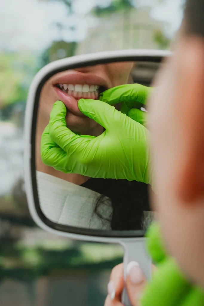 Dentiste évaluant le sourire d’une patiente à l’aide d’un miroir lors d’une consultation esthétique.