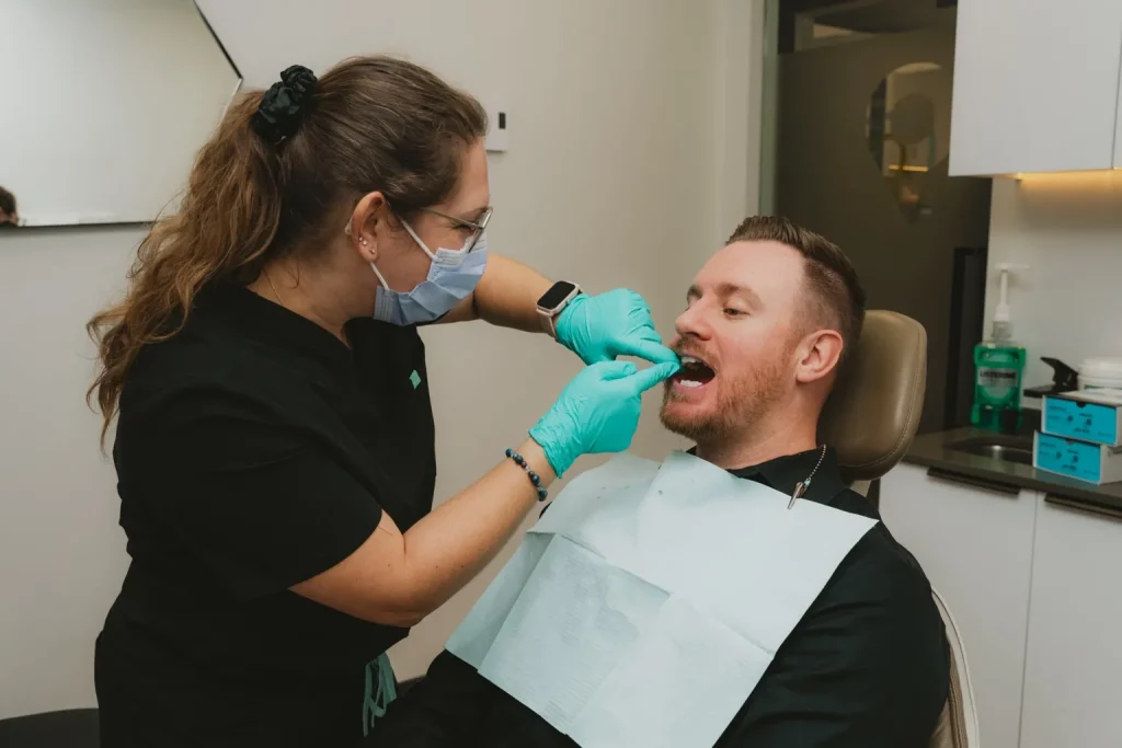 Hygiéniste dentaire effectuant un examen buccal sur un patient lors d’un rendez-vous en clinique dentaire