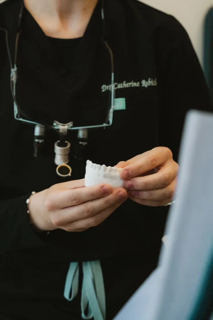 Dentiste présentant un modèle dentaire pour expliquer un traitement à une patiente.