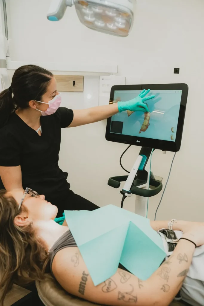 Dentiste présentant un scan 3D des dents à une patiente lors d’une consultation