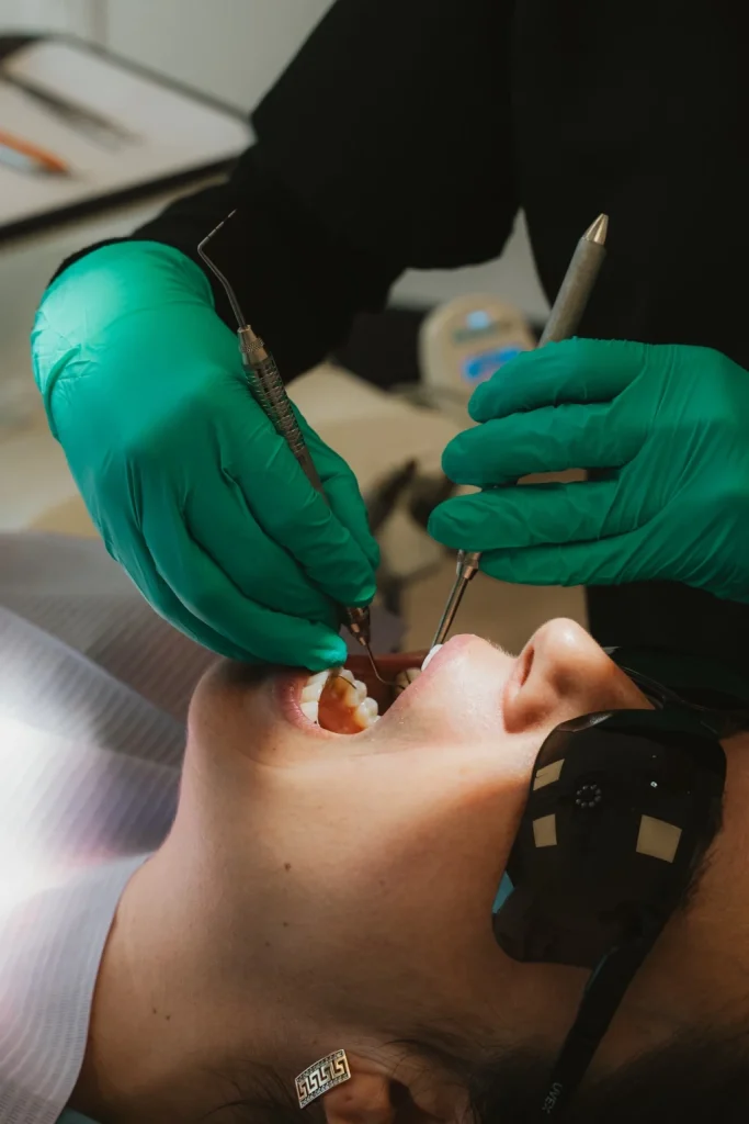 Dentiste réalisant un soin dentaire avec des instruments de précision sur une patiente.