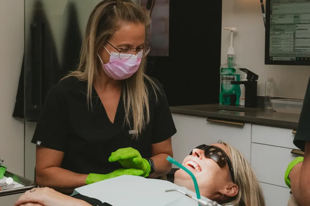 Membre du personnel dentaire souriant avec une patiente détendue en salle de traitement au Centre dentaire Boucherville
